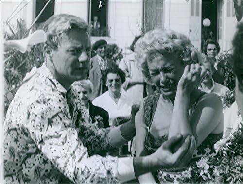 תצלום וינטג 'של מרטין קרול בוכה כמעשה, בעוד שגבר מנחם אותה .- 1956